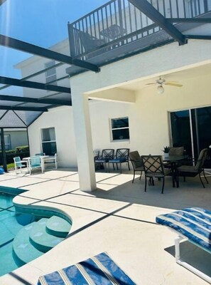 Un'area esterna coperta con piscina, sdraio e tavolo con sedie.