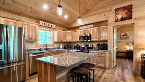 Eine moderne Küche mit Holzschränken, Edelstahlgeräten, Granit Arbeitsplatten und einer zentralen Kochinsel mit Sitzgelegenheiten.