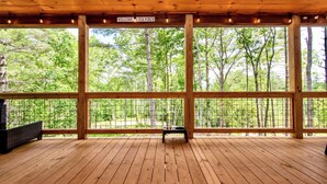 Eine Holzveranda mit einem Schild 'Welcome to Our Porch', großen Fenstern und einer Bank.