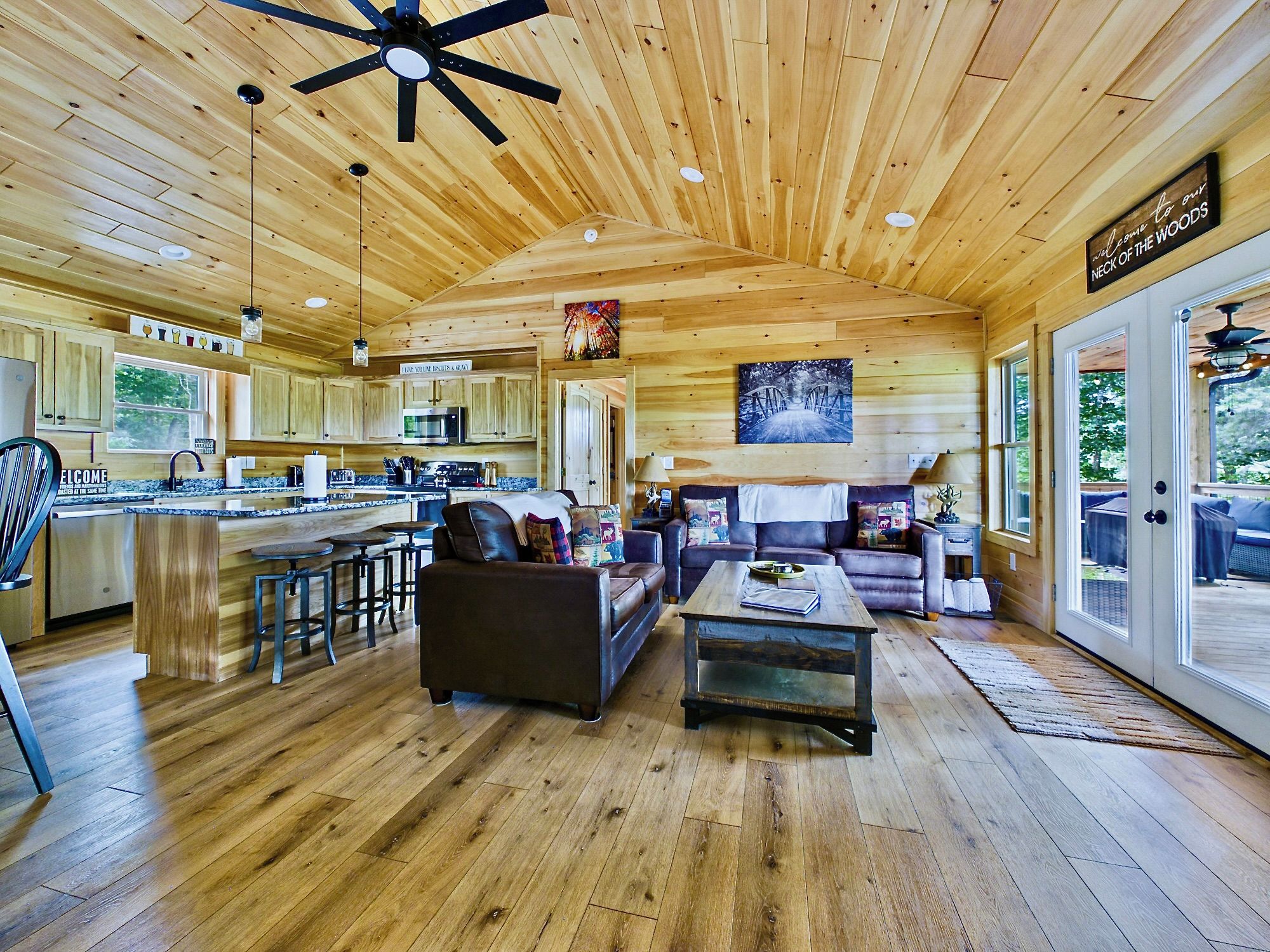 A spacious wooden cabin interior with a kitchen, dining area, and living room.