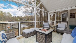 Une terrasse extérieure couverte, aménagée avec des meubles en osier, un foyer et offrant une vue sur les environs.