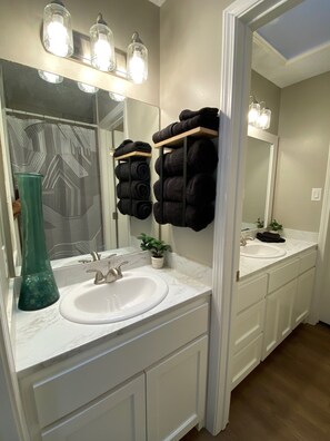 A bathroom with a white sink, a mirror, and a towel rack with rolled towels. - Ideal townhouse for relaxation (Midland)