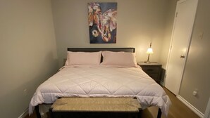 A bedroom with a bed, a nightstand, a lamp, a door, and a rug.