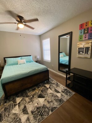 A bedroom with a bed, a ceiling fan, a window with blinds, a mirror, and a rug. - Ideal townhouse for relaxation (Midland)
