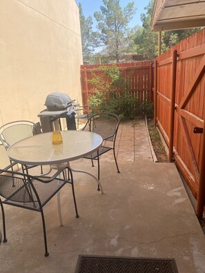 A patio with a round table and chairs, a grill, and a wooden fence. - Ideal townhouse for relaxation (Midland)