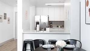 A modern kitchen with white cabinets, a stainless steel refrigerator, and a coffee machine. - Brand New Luxe Apt | 2Mins to Stadium, Free Parking & WiFi, City Views (Charlotte)