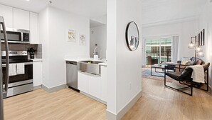 A modern kitchen with stainless steel appliances, a dishwasher, and a white countertop. - Brand New Luxe Apt | 2Mins to Stadium, Free Parking & WiFi, City Views (Charlotte)
