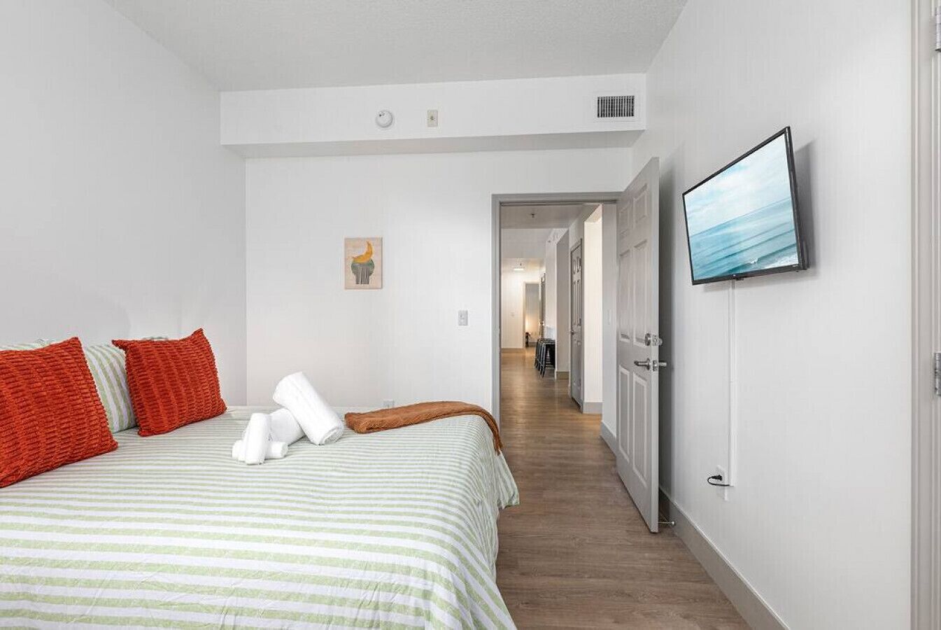 Une chambre d’hôtel avec un lit, des oreillers, une télévision et un couloir menant à une autre pièce.