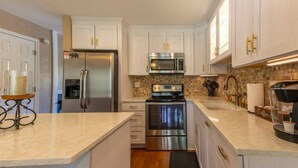 A modern kitchen with white cabinets, stainless steel appliances, and a stone backsplash. - Golf & Lake View Retreat - Rumbling Bald Resort Amenities, Sleeps 6 (Lake Lure)