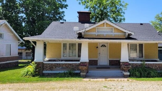 A single-story house with a front porch, a chimney, and a well-maintained lawn. - AV    Bungalows   #2 (Arcadia)