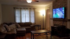 A living room with a sectional sofa, a coffee table, a television mounted on the wall, and a floor lamp. - AV    Bungalows   #2 (Arcadia)