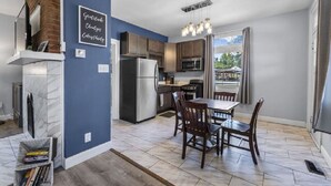 Une cuisine moderne avec un mur d’accent bleu, des armoires en bois et un coin repas comprenant une table et des chaises.