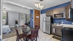 Une cuisine moderne équipée d’un réfrigérateur, d’une cuisinière et de meubles de rangement en bois. On y trouve également un coin repas avec une table et des chaises.