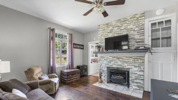 Una sala de estar con chimenea, ventilador de techo y televisor.