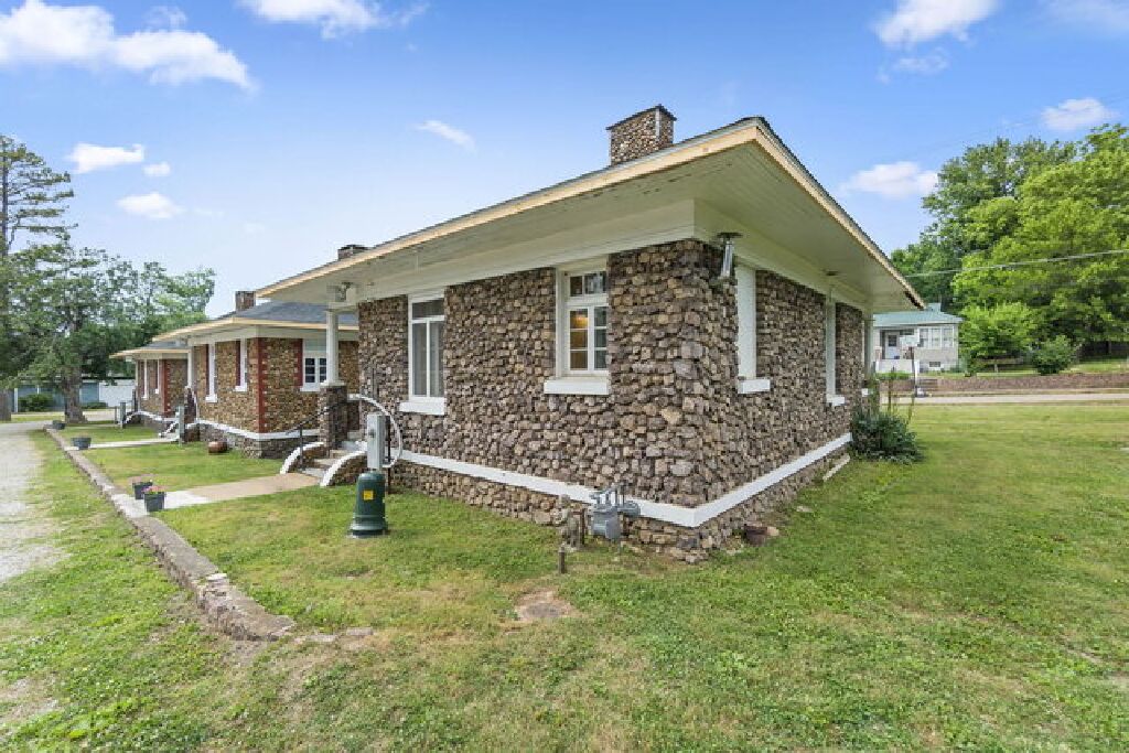 A two-story stone house with a gabled roof and a front porch.