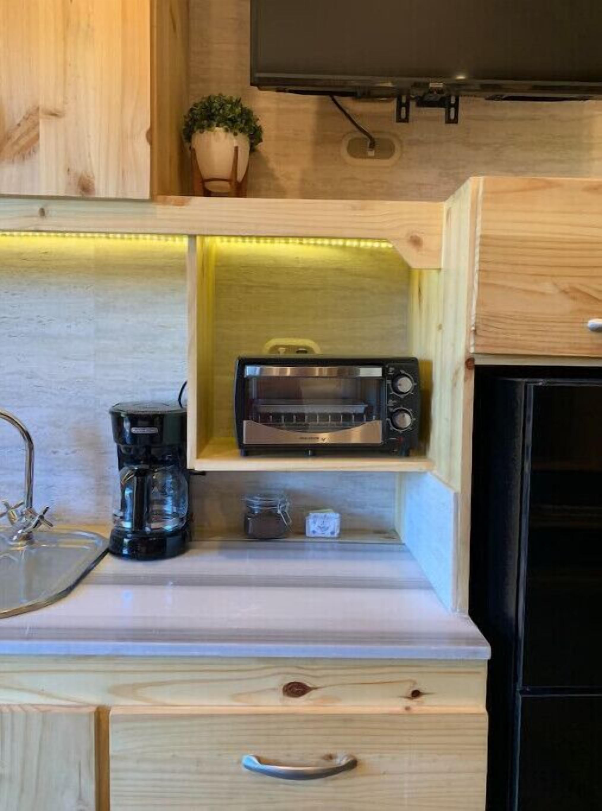 Una cocina compacta con tostadora integrada, cafetera y un mueble pequeño.