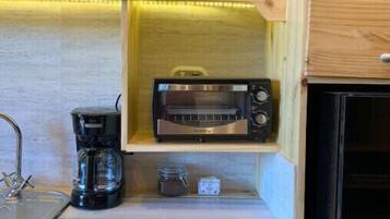 Una cocina compacta con tostadora integrada, cafetera y un mueble pequeño.
