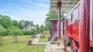 Ein rotes Fahrzeug steht auf einer Auffahrt, mit einem weißen Stuhl und Tisch auf der Veranda.