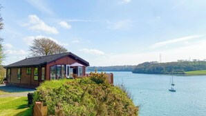 A lakeside cabin with a deck overlooking the water, surrounded by greenery. - 2 bedroom accommodation in Burton (Burton)