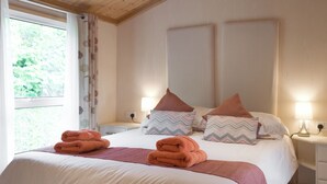 A bedroom with a large bed, two bedside tables, and a window with curtains. - 2 bedroom accommodation in Burton (Burton)