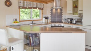 A modern kitchen with a central island, stainless steel appliances, and a window providing natural light. - 2 bedroom accommodation in Burton (Burton)
