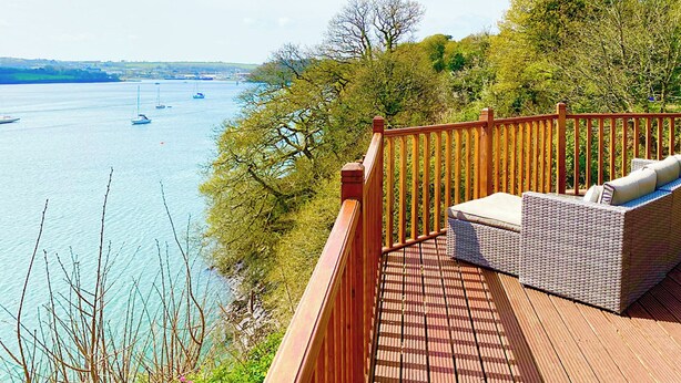 A wooden deck with a wicker sofa overlooking a body of water with boats. - 2 bedroom accommodation in Burton (Burton)
