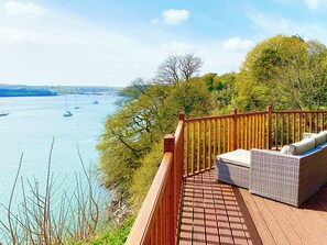 A wooden deck with a wicker sofa overlooking a body of water with boats. - 2 bedroom accommodation in Burton (Burton)
