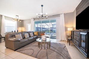 Un salon moderne avec un canapé d’angle, une table basse en verre et une vue sur l’extérieur.