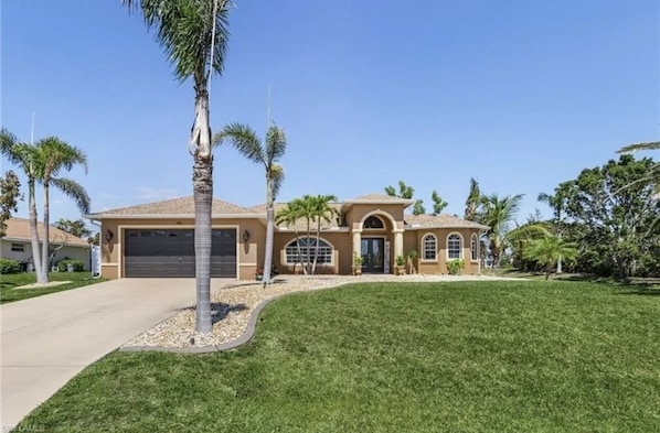 A two-story house with a garage, a covered patio, and a well-maintained lawn.