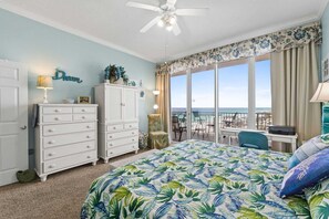 Un dormitorio con cama, cómoda, silla, escritorio y balcón con vistas.