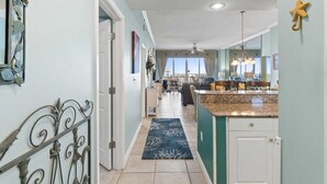 A spacious kitchen with a large island, a dining area with a view, and a hallway leading to a door.