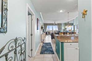 A spacious kitchen with a large island, a dining area with a view, and a hallway leading to a door.