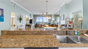 A spacious kitchen with granite countertops, a stainless steel sink, and a dining area with a view.