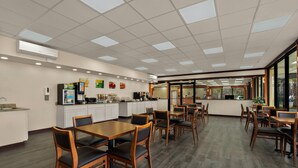 A spacious dining area with multiple tables and chairs, a kitchen area with appliances, and large windows providing natural light. - Quality Inn Yemassee - Point South I-95 (Yemassee)