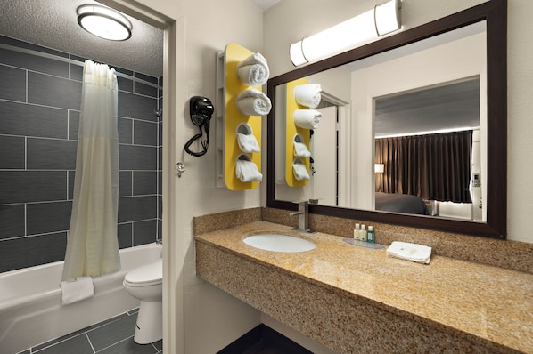 A bathroom with a bathtub, toilet, sink, and a mirror with a towel rack.