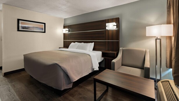 A hotel room with a bed, a chair, a desk, a lamp, and a picture on the wall. - Quality Inn Yemassee - Point South I-95 (Yemassee)