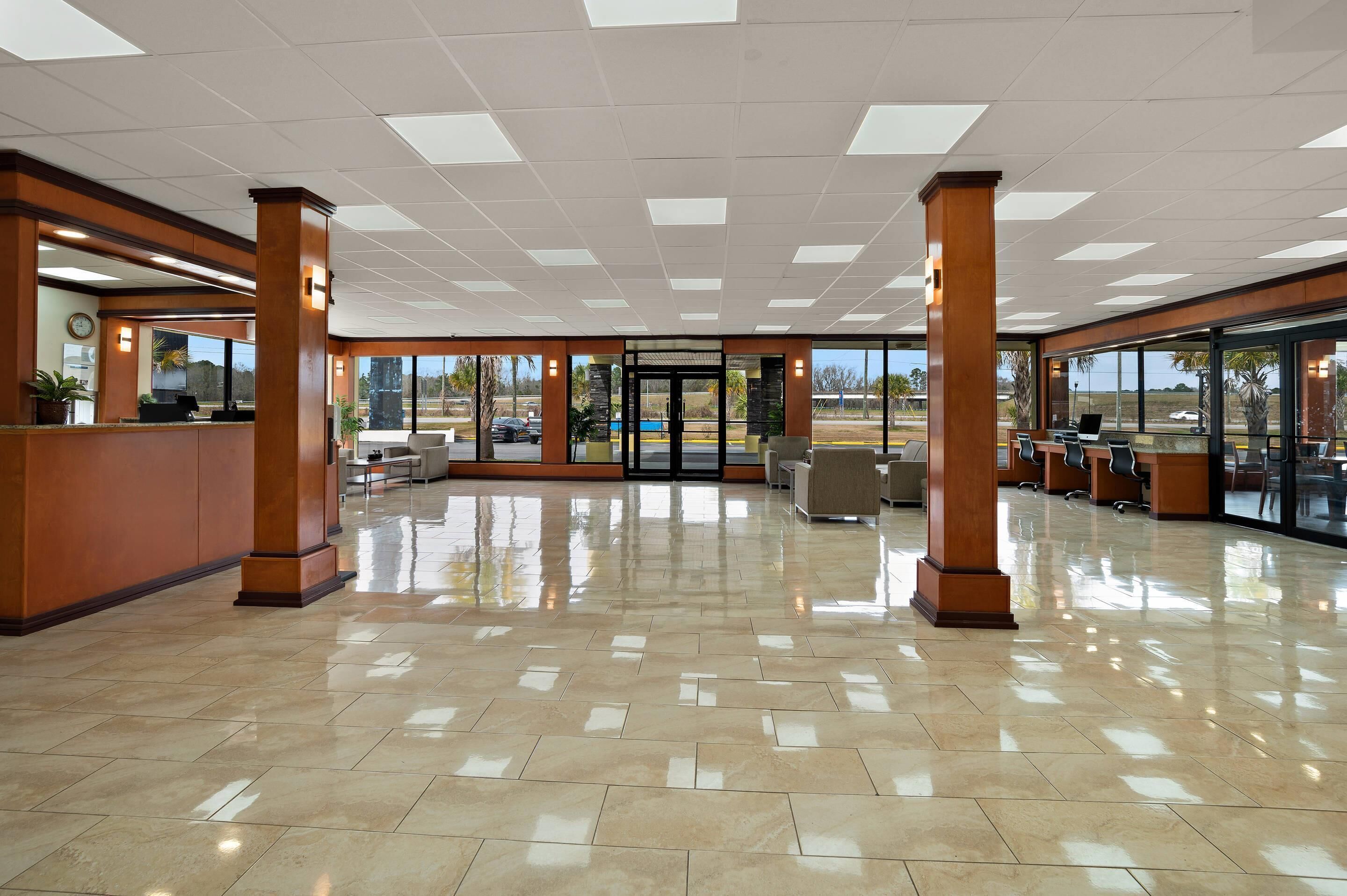 A spacious lobby with a tiled floor, wooden pillars, and a reception desk.