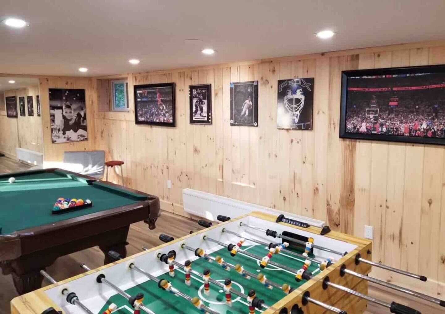 Ein Raum mit Billardtisch, Kicker und Sportmemorabilien an den Wänden.