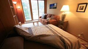Une chambre à coucher avec un lit, un canapé, une lampe et une fenêtre donnant sur un beau paysage.