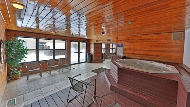 Un intérieur en bois avec une grande fenêtre, un jacuzzi et un coin salon.