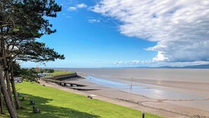 A coastal landscape with a grassy area, a paved walkway, and a view of the sea. - The Court House - UK43908 (Silloth)