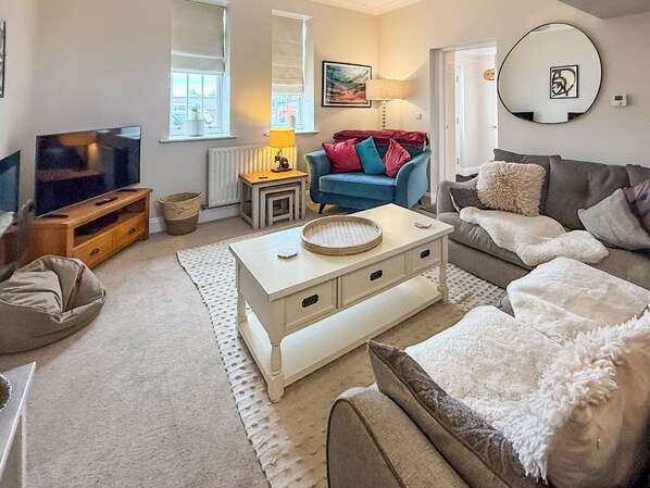 A living room with a television, a sofa, a coffee table, and a lamp.