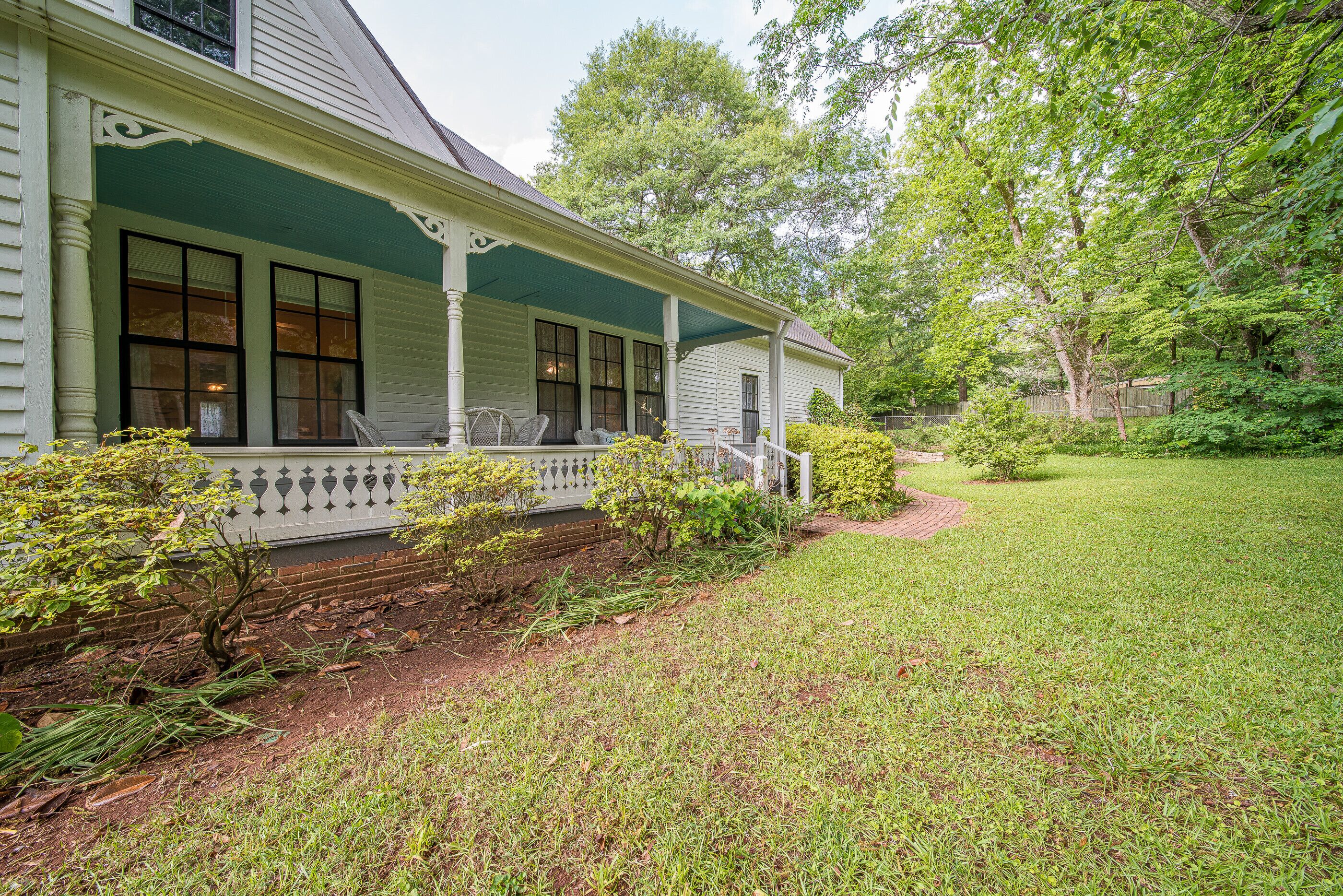 A house with a porch, a brick pathway, and a well-maintained lawn.