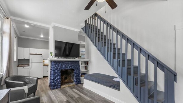 A modern living room with a stone fireplace, a dining area with a table and chairs, and a blue staircase. - AV Bungalows #9A with Loft (Arcadia)