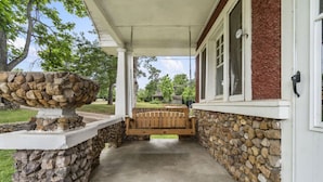 A covered porch with a stone wall, a wooden bench, and a stone planter. - AV   Bungalows    #8 (Arcadia)