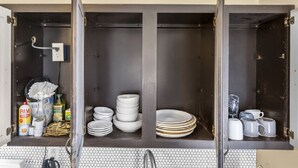 A kitchen with open cabinets displaying stacked plates, bowls, and mugs. - AV   Bungalows    #8 (Arcadia)