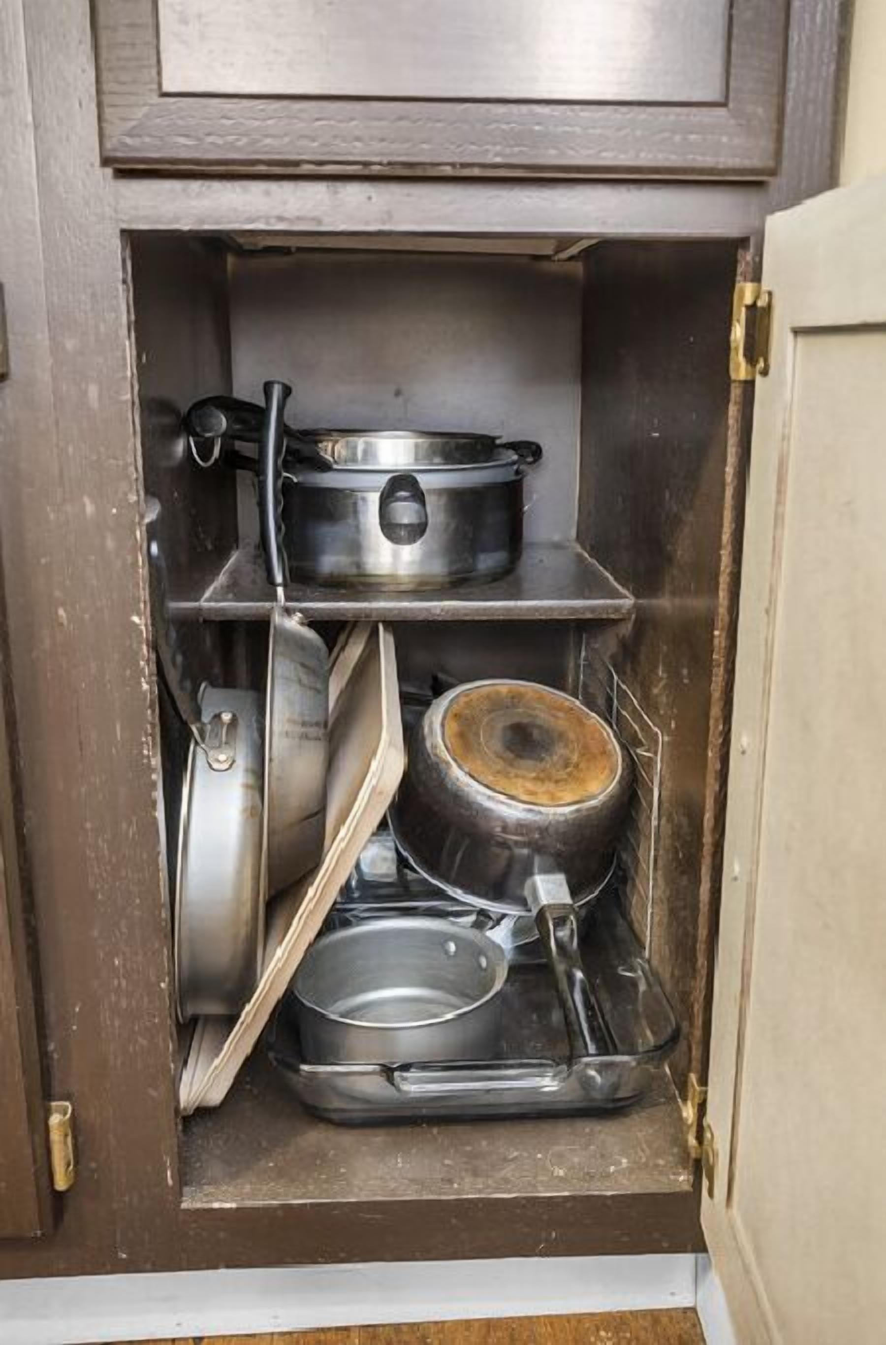 Un meuble de cuisine contenant divers ustensiles de cuisine, notamment des casseroles, des poêles et une cuisinière.