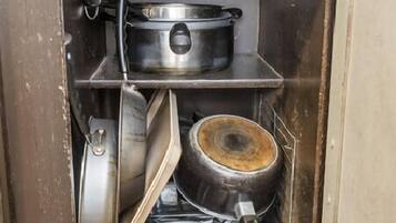 Un meuble de cuisine contenant divers ustensiles de cuisine, notamment des casseroles, des poêles et une cuisinière.