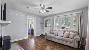 A spacious living room with hardwood flooring, a beige sofa, a ceiling fan, and a television on a stand. - AV    Bungalows   #7 (Arcadia)