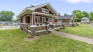 A two-story house with a stone foundation, a front porch, and a small attached garage. - AV    Bungalows   #7 (Arcadia)
